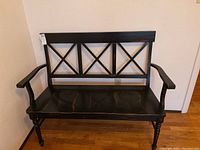 Full front view of the black wooden two-seater bench showing its structure and finish.