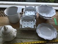 All ceramic items displayed on table - rice pot, plant pot, two strainers, and garlic holder.