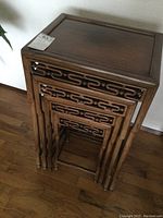 Four nesting tables stacked inside each other against wall on wood floor