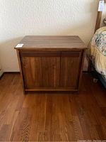 Front view of one wooden night stand showing flat top, drawer, and cabinet doors.