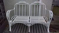 Full front view of white metal loveseat showing overall design and condition