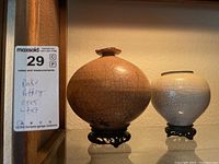Two raku pottery vases on teak stands, showing overall shapes and crackle glaze surface patterns.