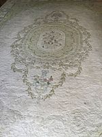 Full view of wool area rug showing central floral medallion and overall cream color