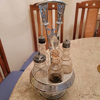 Front and top angled view of metal cruet holder with four glass bottles placed on a countertop.