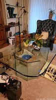 Full view of custom thick rounded edge glass coffee table in a living room setting showing top surface and surrounding decor.