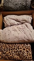 Box containing light pink pajamas with black polka dots and beige leopard print pajamas