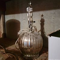 Mercury glass lamp with ribbed round base and metal stand under low lighting.