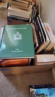 Top view of a box filled with various books including the green Alpha Delta Phi 2018 catalogue and other assorted books stacked sideways.