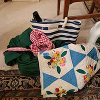 Mixed lot includes quilt, green fabric garment, red gingham garment, striped bag with umbrella inside