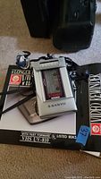 Sanyo portable cassette player with attached headphones on top of VHS UV-810 box.