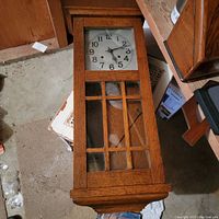 Full view of rectangular oak wall clock case lying face up showing front glass panel with wood grid