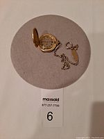 Top view of the open pocket watch showing face and attached chain spread on round felt pad.