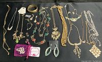 Full overview of all jewelry items laid out on black fabric showing variety of styles including necklaces, earrings, bracelets, and cuff links.