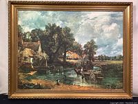 Full view of the large framed canvas print depicting a wagon crossing a river near a cottage with a dog, set against a cloudy sky and rural landscape.