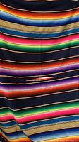 Full view of colorful striped serape blanket with visible color bands and some fabric texture.