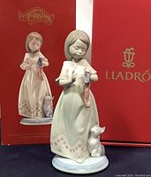 Photo showing front of Lladro figurine with girl holding stocking and kitten, with original box behind.