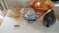 Wide view of all four items shown together: two carnival glass bowls, Japanese teapot, and plastic decoy duck