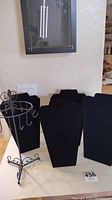 Four black velvet jewelry display bust forms and one metal jewelry display stand seen from front showing their shapes and condition.