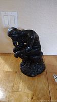 Side view of the black Thinker statue figurine showing the seated male figure with hand on chin.