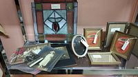 Vintage stained glass panel, assorted vintage photo frames and black & white photos arranged on a shelf
