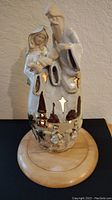 Front view of vintage ceramic nativity tea light figurine with Mary, Joseph, and baby Jesus. Mounted on a round wood base.