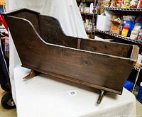 Side profile showing full length of antique cradle with rocker base and high headboard