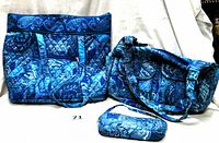 Three blue paisley print bags: large tote, shoulder bag, and wristlet displayed together on a white surface.