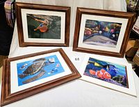 Four lithograph prints from Pixar Finding Nemo, three framed and one with mat, glass and backing unframed on display.