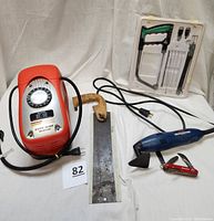 Full lot showing Black & Decker air station, wooden handled pull saw, electric detail sander, magic saw kit in white plastic packaging, and small red folding multi-tool.