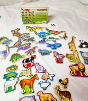 Image showing the colorful wooden magnetic animals arranged on a white surface alongside their labeled packaging box displaying the brand and set information.