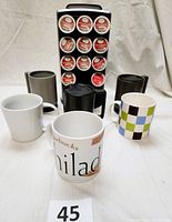 Photo of three Starbucks ceramic mugs of different colors with lids and Keurig K-Cup carousel holder with tea pods