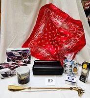 Full lot laid out showing red Orvis bandana, Mario Andretti collectible tin with cards, ceramic horse mug, shaving soap, and 17-inch brass horse head shoe horn.