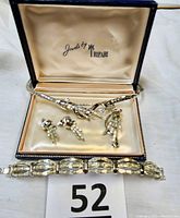 Photo showing complete Trifari set in original blue satin-lined jewelry case, including necklace, bracelet, earrings, and pin.