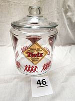 Front view of the clear glass Twix cookie jar with lid on, showing logo and marching band design.