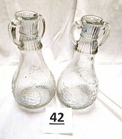 Pair of clear crackle glass White House Vinegar decanters with double handles and embossed floral design.