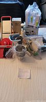Wide view of all items on a bed showing mandoline slicer, meat grinder, spiralizer in box, and chopper in packaging