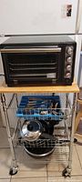 KitchenAid countertop oven on a metal rack with kitchen utensils below and beside it