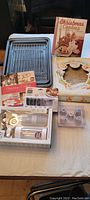 Set of cookie sheets and cooling racks laid out flat, plus two cookbooks and cookie press with extra disks