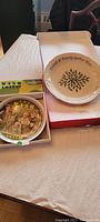 Photo showing the MASH 4077th limited edition plate with a picture from the series and box, and the Lenox holiday dessert platter with its box and certificate.