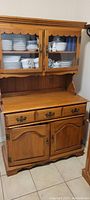 Full view of mid-century rustic pine China Hutch showing upper glass doors with interior shelves and lower drawers and cabinet