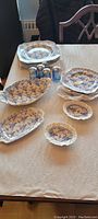 Photo showing all items together on table, including plates, serving dishes and 4 salt and pepper shakers.