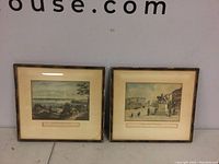 Two framed prints side by side with visible chipping and wear on frames and matted color prints of New York City landmarks.