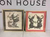 Both framed temple rubbings side by side showing decorative figures. One framed with black mat, one with red mat.