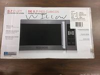 Box front showing the 0.7 cubic feet Black and Decker microwave oven with product details in English and Spanish.