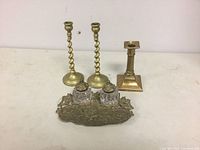 Full view of all four items together showing the pair of twisted brass candlesticks, single brass candlestick, and brass dragon inkstand with two glass inkwells.