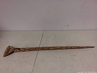 Full shot of the carved wooden walking stick showing its length and carvings.