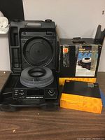 Kodak 5600 Carousel Slide Projector setup showing main unit, original Kodak Carousel box, Sawyer's Rototray slide tray box with Kodak branding, all placed on a surface under indoor lighting.