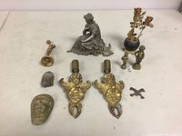 Collection of all metal items including seated woman clock topper, pair of brass cherubs, vase with roses sculpture, basketball trophy topper, and small decorative pieces