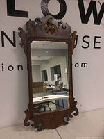 Full view of carved wood framed rectangular mirror showing detailed edge designs and reflective mirror surface.