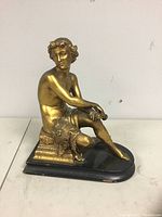 Front and left side view of the patinated metal sculpture seated on a wooden base showing overall figure and base condition.